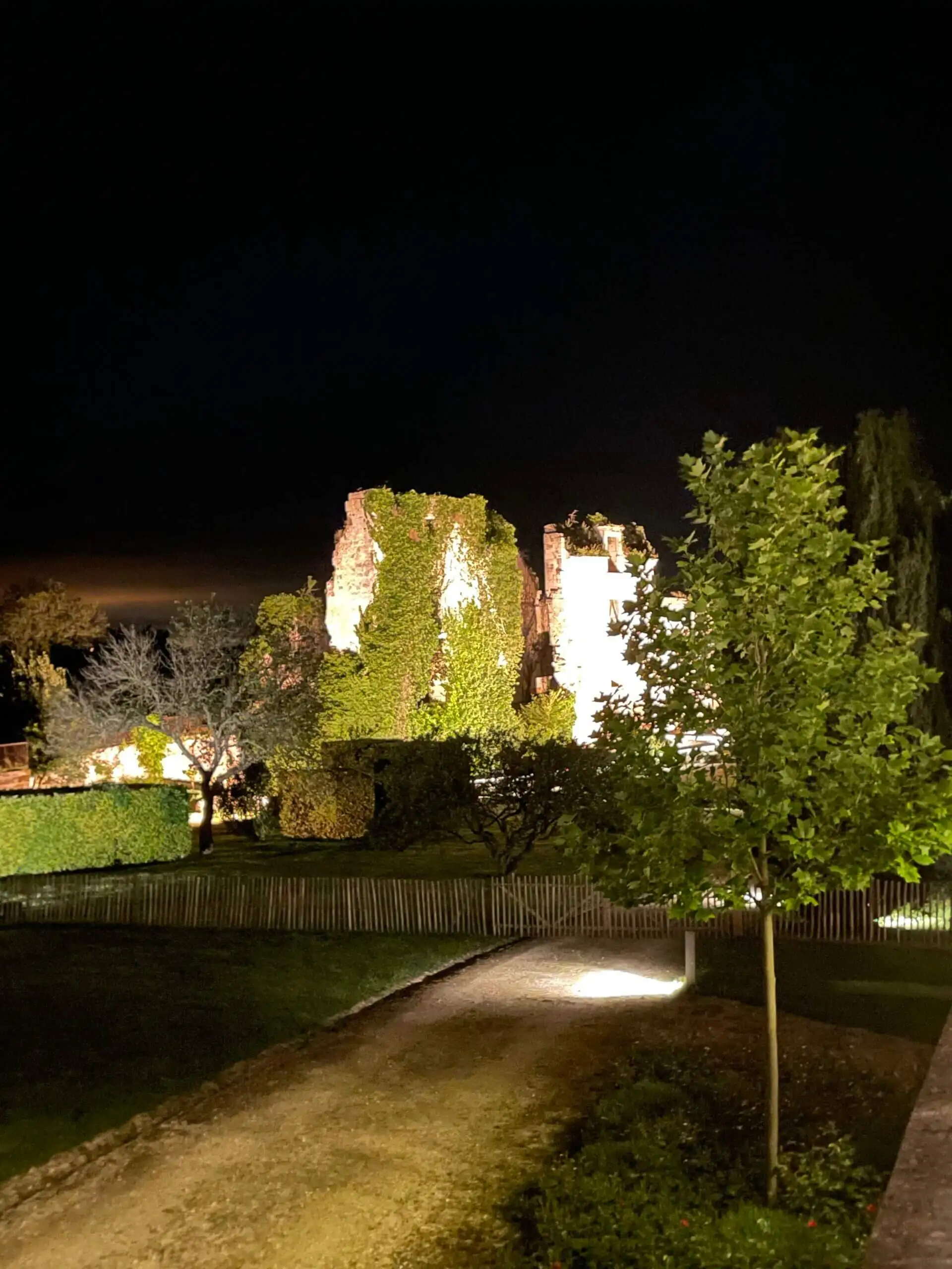 Allée d'un château balisée de lumières dans la nuit