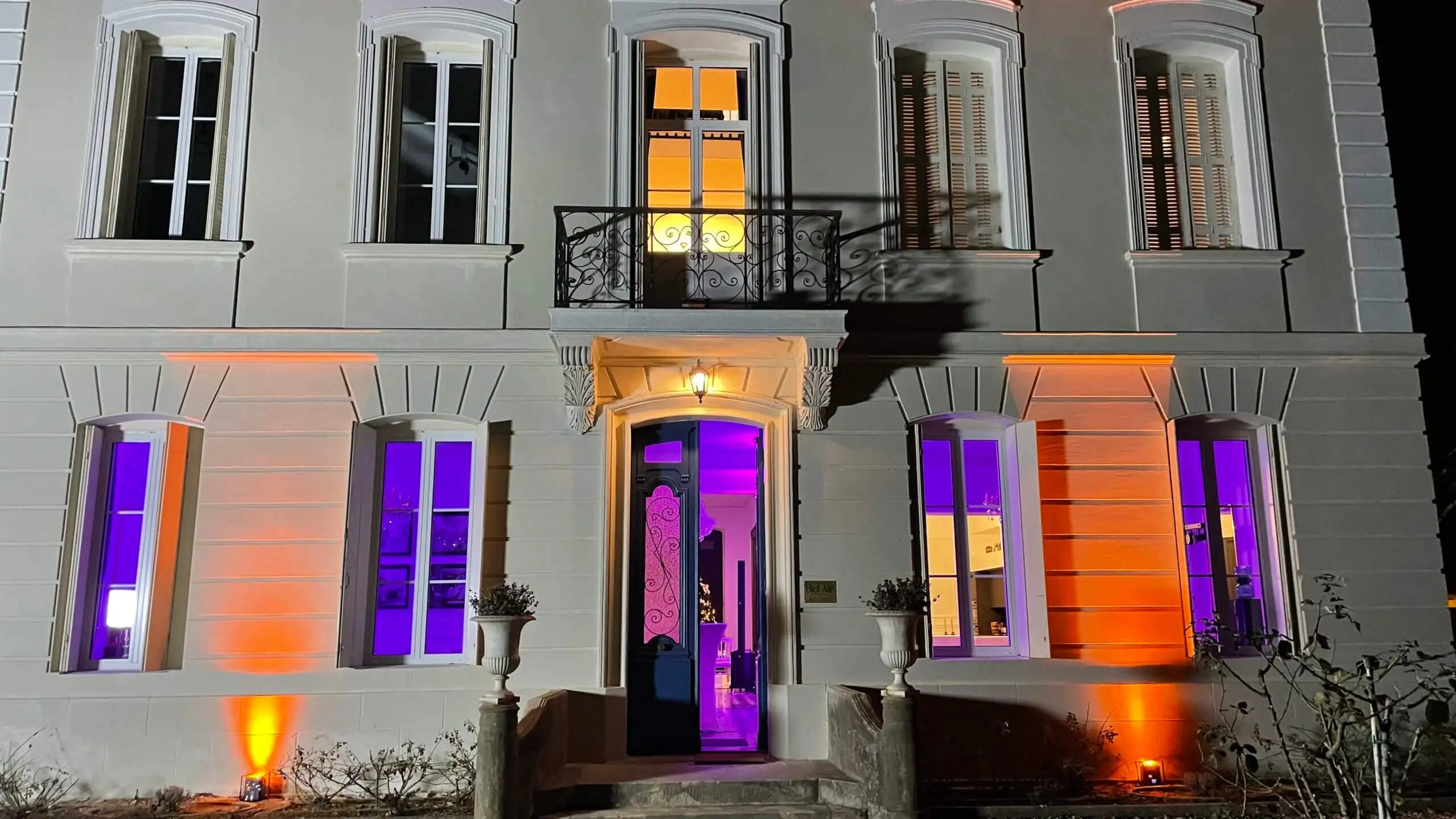 Façade d'un château mise en lumière en orange et violet à la nuit tombée
