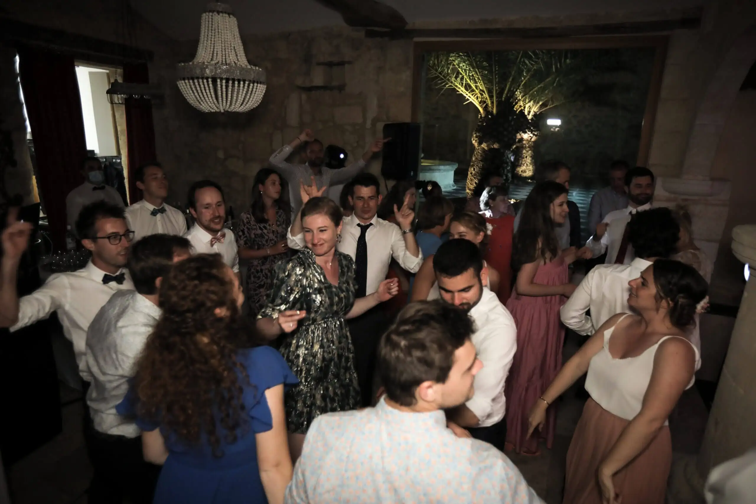 Invités qui dansent sous un lustre en cristal dans une salle en pierre