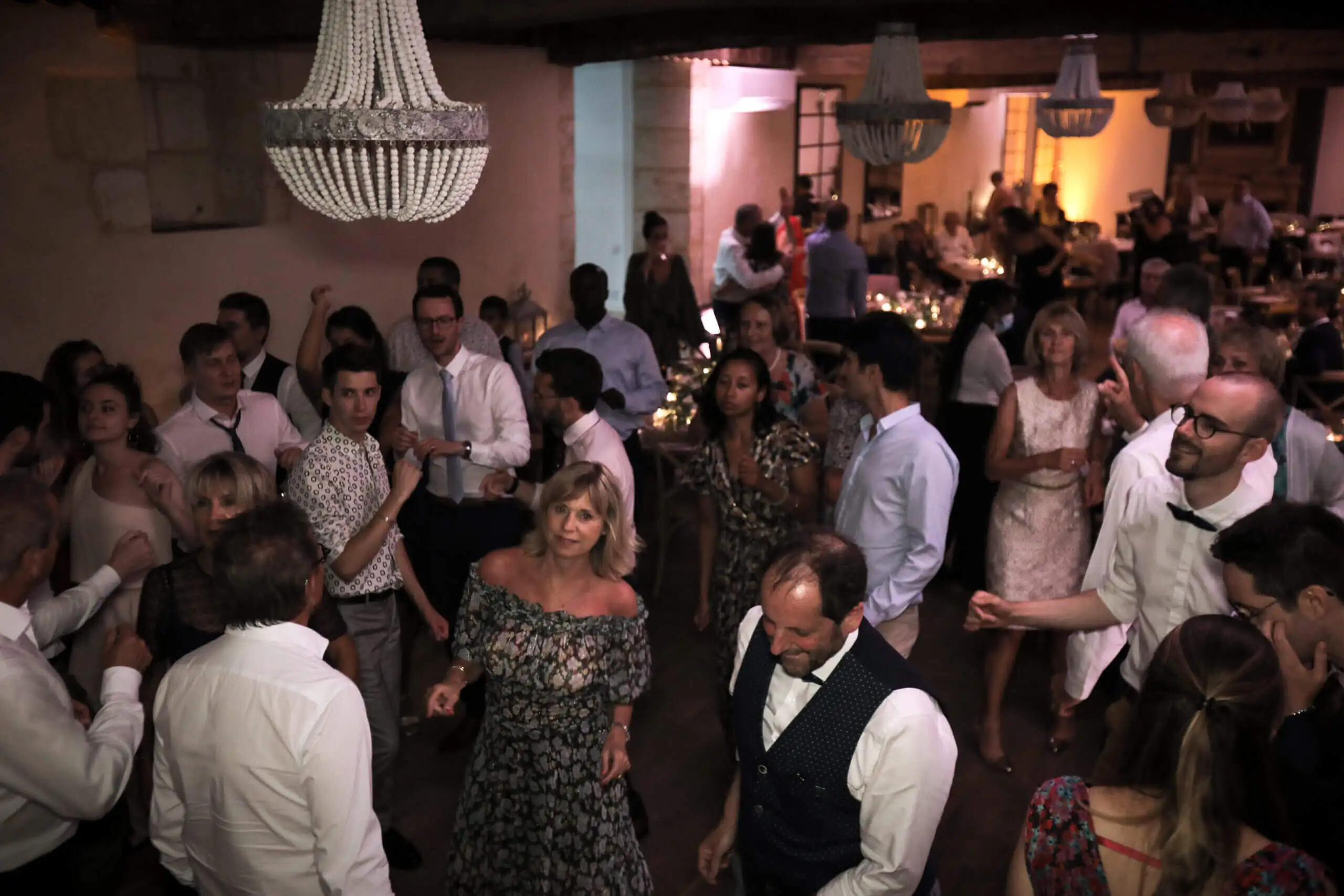 Piste de danse pleine sous un lustre, invités en tenue de soirée