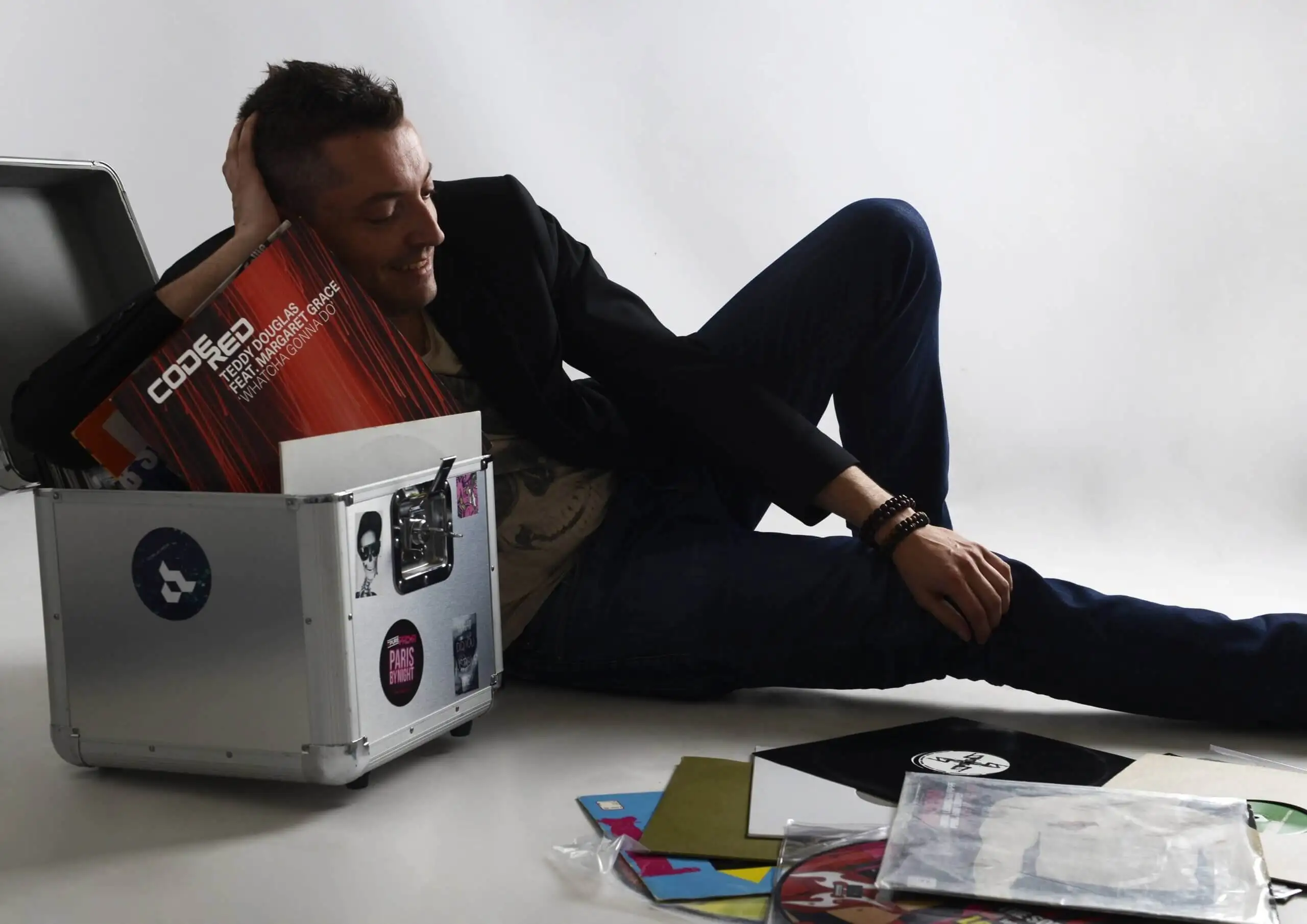 Tom Emersson allongé en studio à côté de son flight case et de ses vinyles