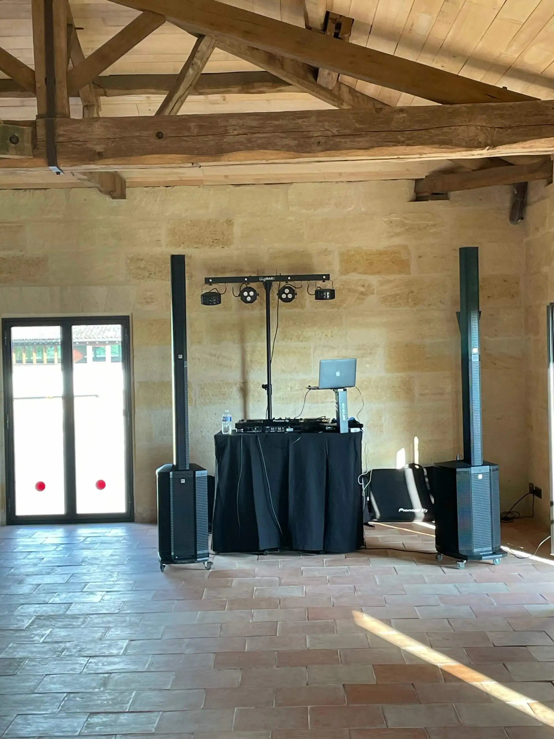 Régie DJ et enceintes installées dans une salle en pierre avant les invités