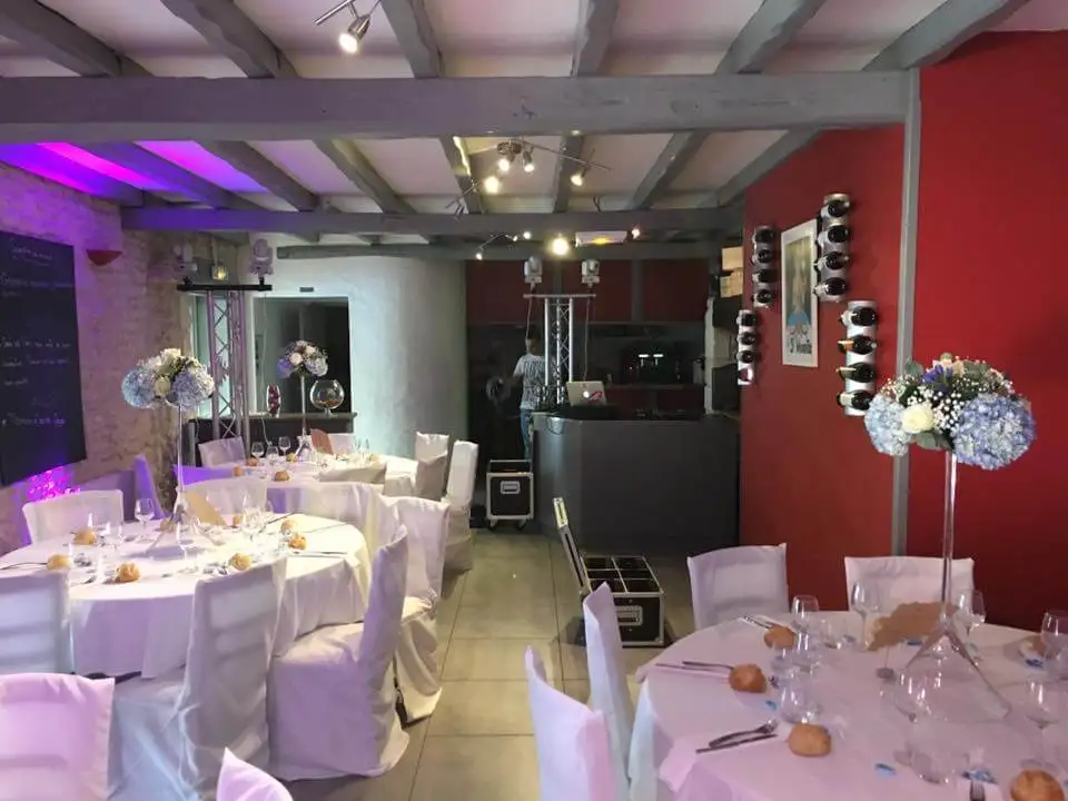 Salle de réception aux murs rouges, tables dressées et éclairage d’ambiance