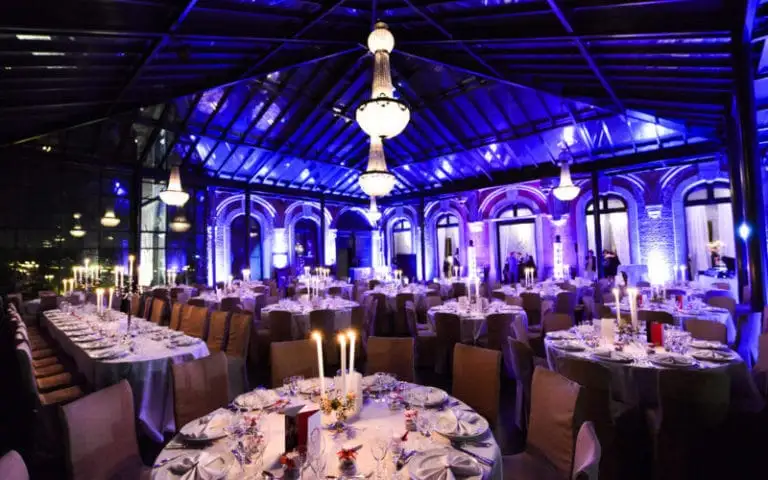 Salle de réception d’entreprise mise en lumière en bleu, tables dressées